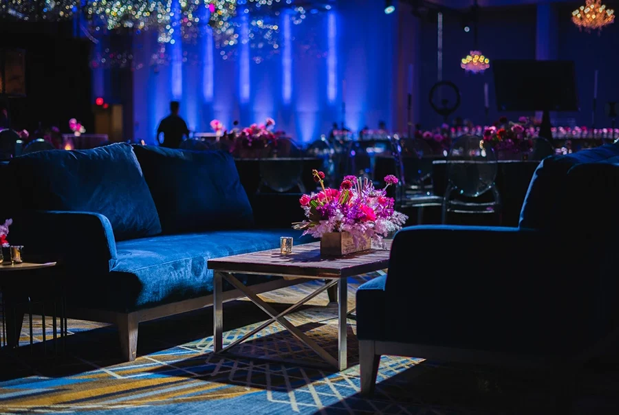 Event Rentals — seating arrangement with colorful floral centerpiece, full service AV on display in background