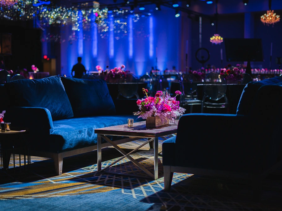 Event Rentals — seating arrangement with colorful floral centerpiece, full service AV on display in background