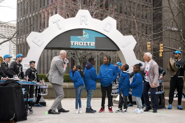 Community event at the NFL Draft countdown clock unveiling near Campus Martius with children and a drumline