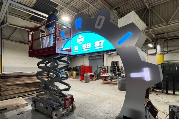 Fabricator on scissor lift testing the NFL Draft countdown clock LED display inside a Detroit production facility