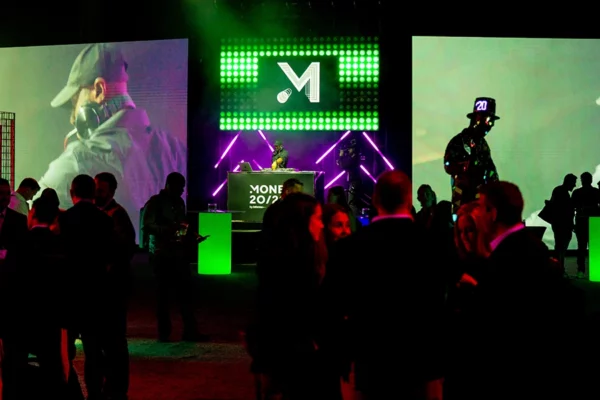Silhouetted attendees at Money 20/20 with green LED branding