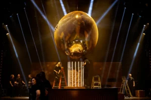 Gold mirror football centerpiece on stage with dramatic beam lighting