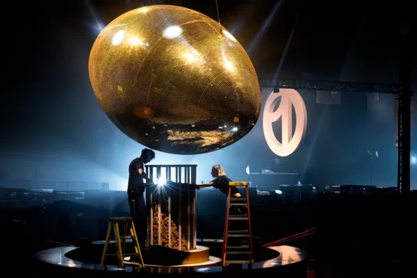 Crew finishing stage installation beneath Uber One gold football