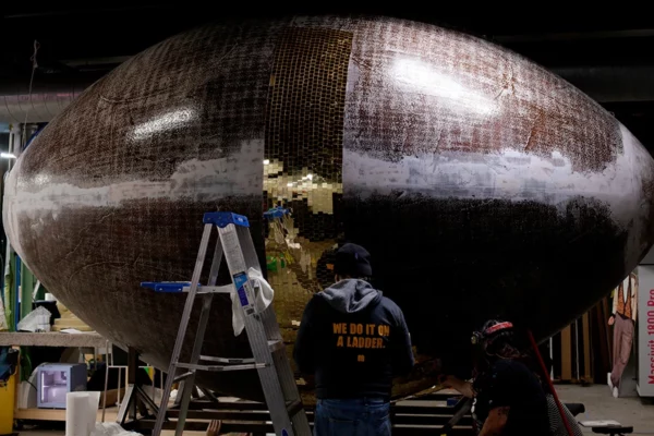 Display Group crew applying gold mirror tiles to oversized football sculpture