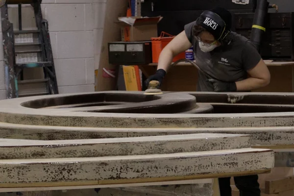 Display Group fabricator sanding football lace detail in shop