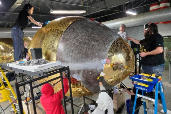 Full Display Group team tiling large gold mirror football sculpture