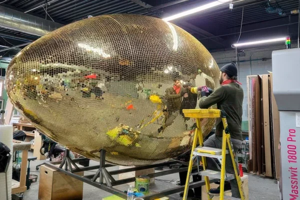 Fabricator finishing gold mirror tile application on football prop