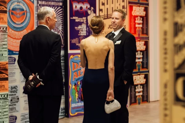 Guests conversing in front of vintage concert poster wall at AHOF event