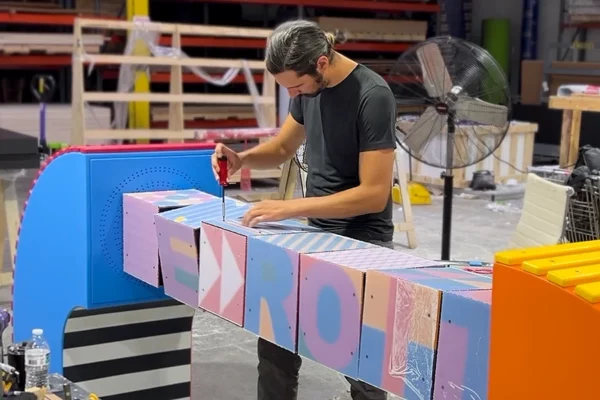 Fabricator assembling colorful lettered panels for Bedrock streetscape sculpture