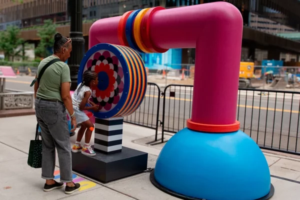 Child and adult interacting with spinning wheel element of Bedrock streetscape