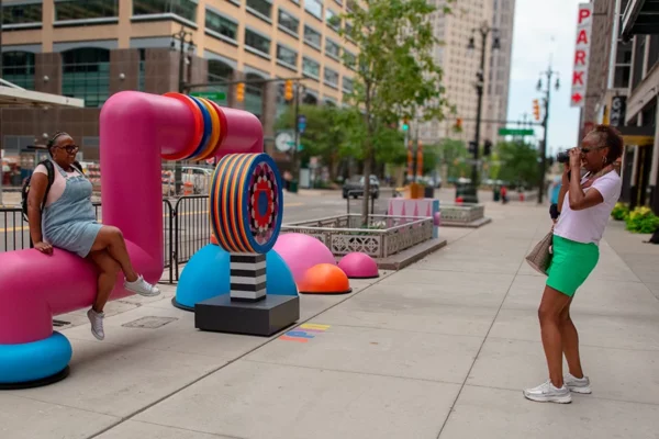 Woman posing for photo on Bedrock streetscape sculpture in downtown Detroit