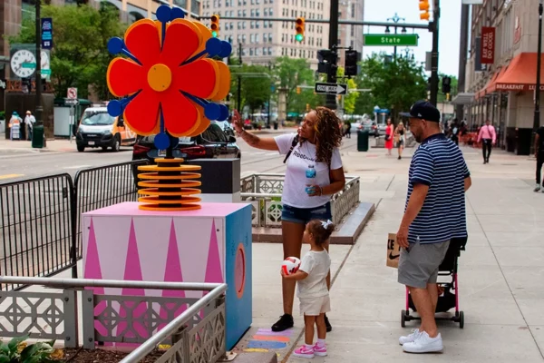 Family interacting with large flower sculpture in Bedrock streetscape