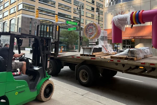 Forklift unloading Bedrock streetscape sculpture components on Woodward Avenue