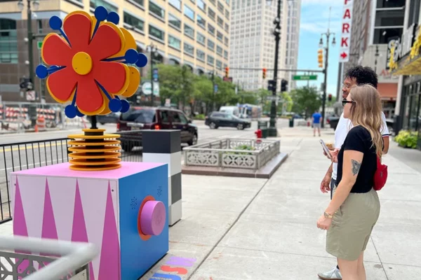 Two pedestrians looking at flower sculpture in Bedrock streetscape Detroit